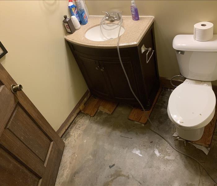 A toilet is clogged with disgusting toilet paper that has overflown onto the floor